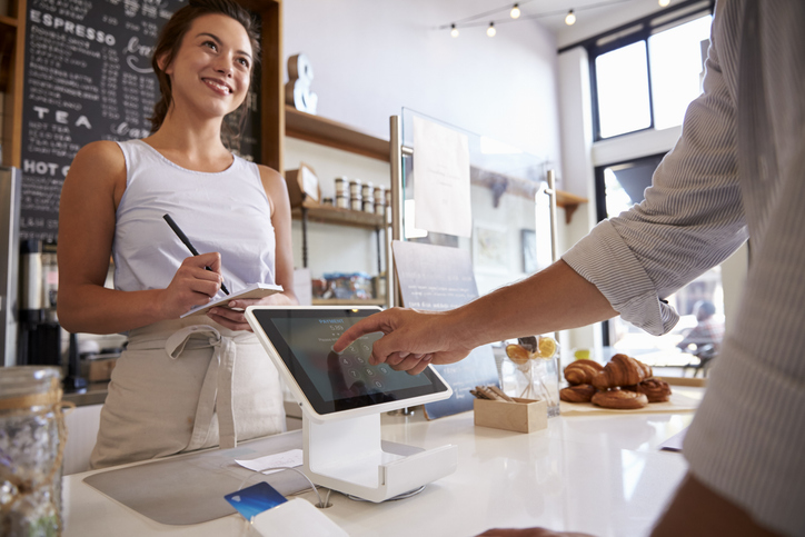 Cliente que utiliza la pantalla táctil para realizar el pago en una cafetería