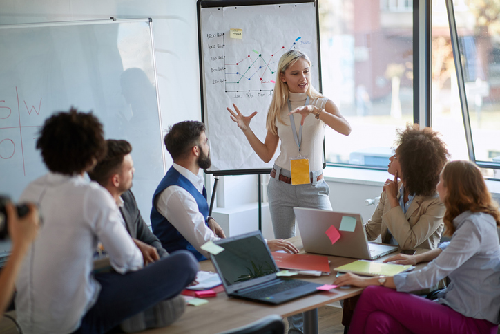 La mujer de negocios presenta su idea al equipo de trabajo. Los colegas de negocios hablan sobre un plan o un nuevo proyecto.